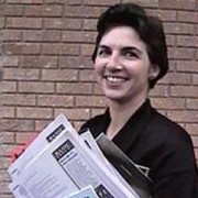 Nicole Grayson woman with short dark hair holding an armful of papers and other items